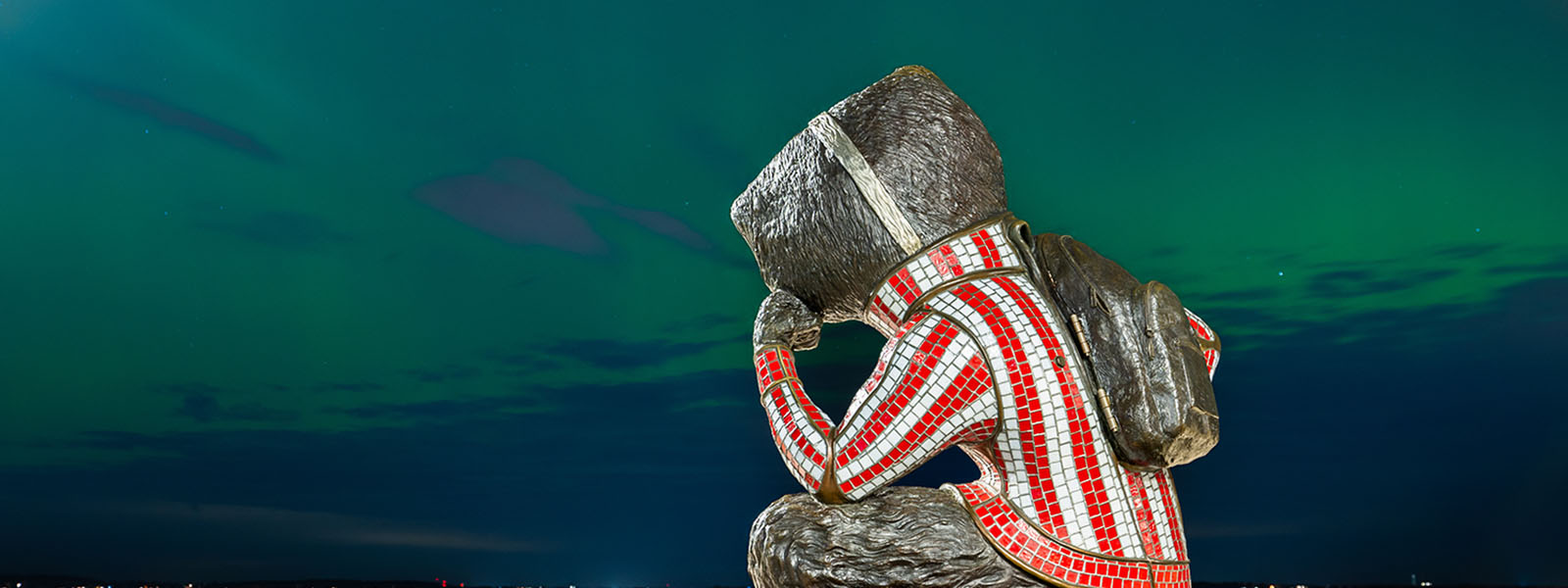 A statue of Bucky Badger with a background of the northern lights in the night sky.